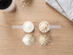 Overhead view of a whey protein scoop and a plant protein scoop with powder next to each, showing different textures