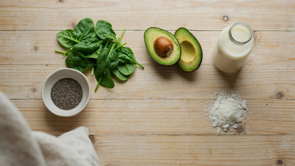 Fresh ingredients for naturally low sugar smoothies arranged on a wooden kitchen counter.