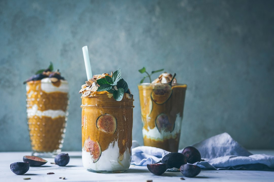 Three colorful keto smoothies in glass jars with healthy fat toppings